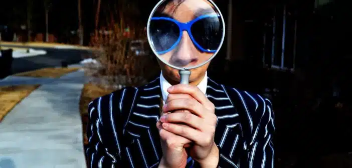 person using magnifying glass enlarging the appearance of his nose and sunglasses